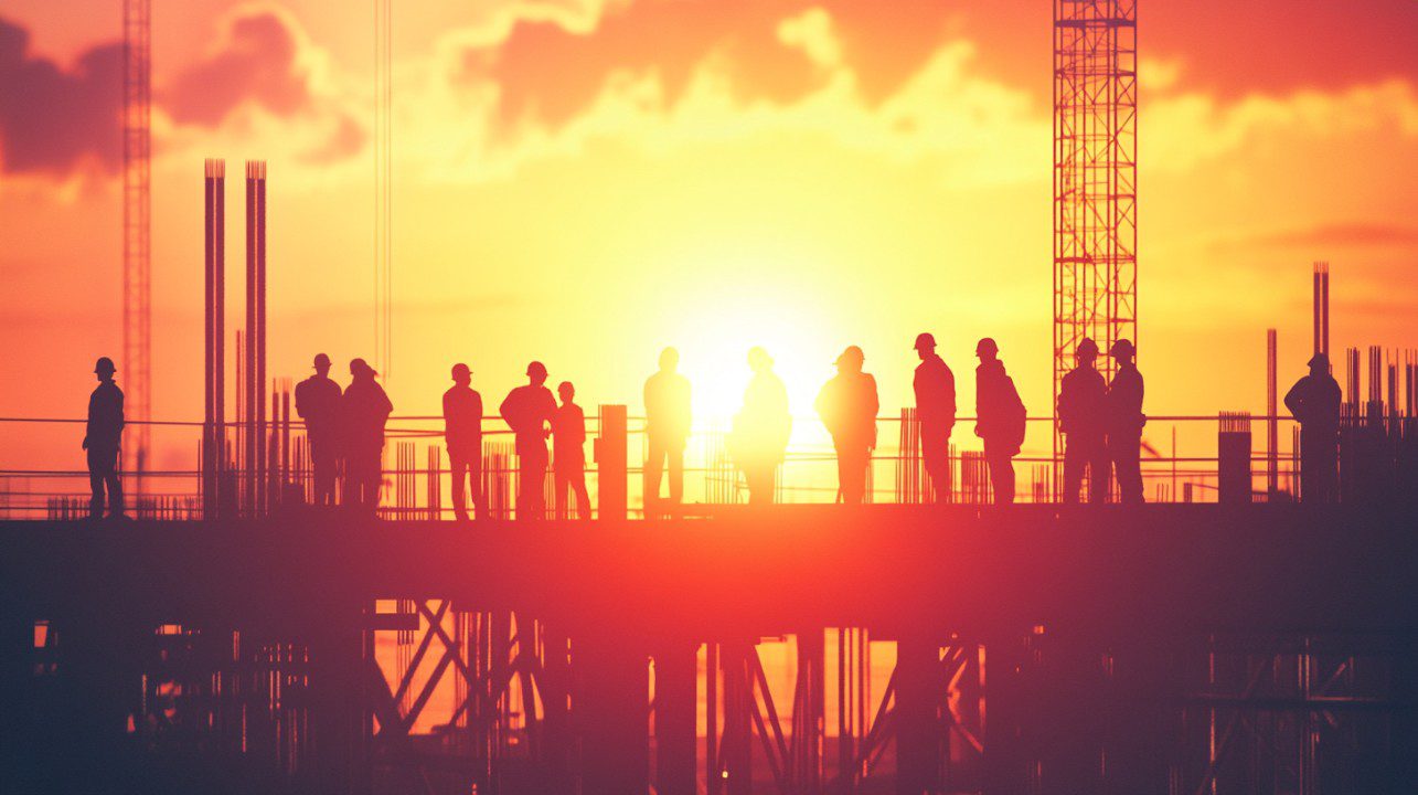 Construction workers at sunset silhouette